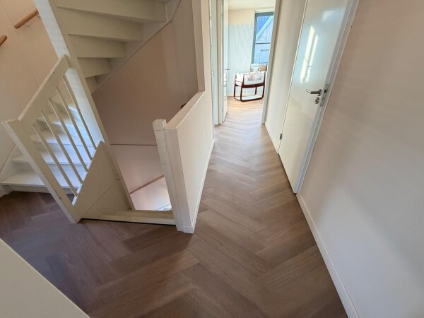 Overloop op de eerste verdieping met een PVC vloer in Weense punt naast de trap