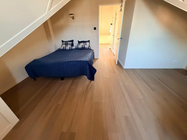 Slaapkamer onder de schuine kap met rechte PVC planken in dezelfde kleur als de Weense punt beneden